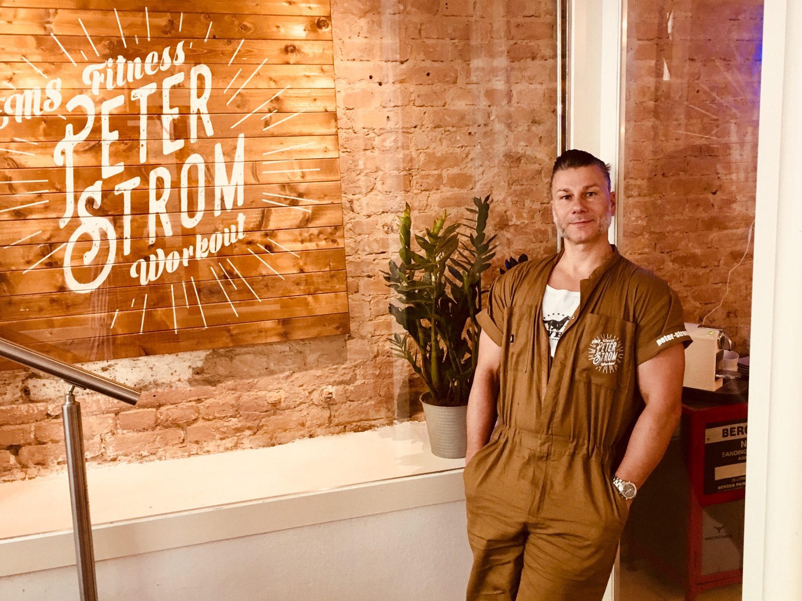Peter im persönlich eingerichteten Studio vor einer Backsteinwand