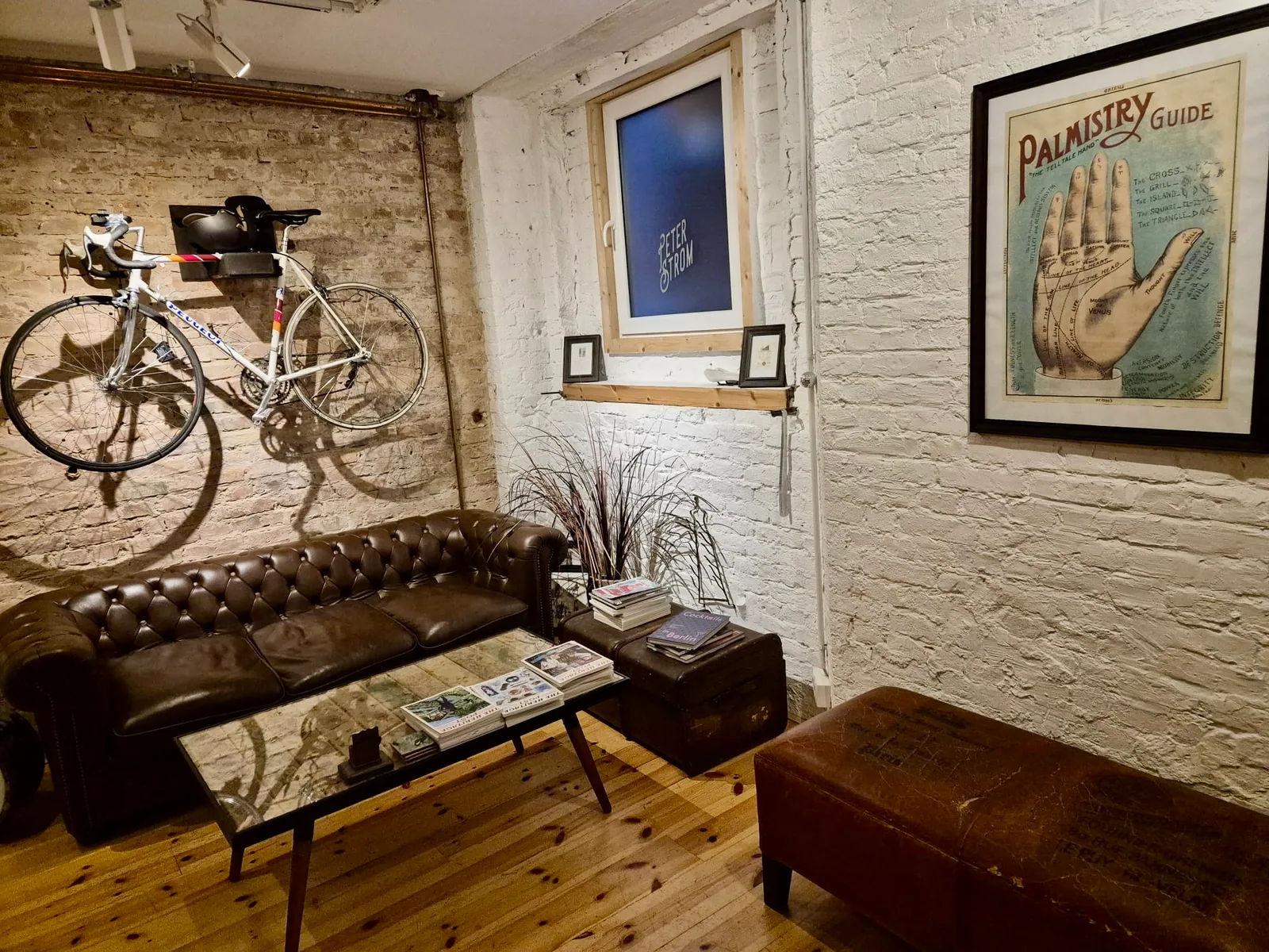 Gemütliche Studio-Lounge mit Ledersofa und Rennrad an der Backsteinwand